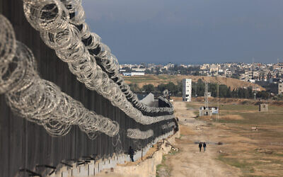 نازحون فلسطينيون يسيرون بجوار السياج الحدودي بين غزة ومصر في رفح، 16 فبراير 2024. (Mohammed Abed/AFP)