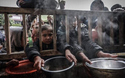 أطفال فلسطينيون نازحون يتجمعون للحصول على الطعام في مدرسة حكومية في رفح بجنوب قطاع غزة، 19 فبراير، 2024 (MOHAMMED ABED / AFP)