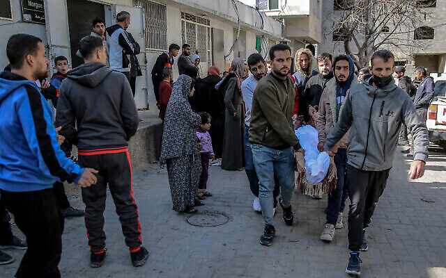 فلسطينيون يحملون جثة رجل من مشرحة مستشفى الشفاء في مدينة غزة، 15 مارس، 2024. (AFP)
