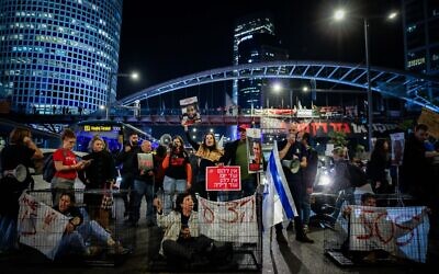 متظاهرون يجلسون في أقفاص لتسليط الضوء على استمرار احتجاز الرهائن الإسرائيليين في غزة، في تل أبيب، 26 مارس، 2024. (Chaim Goldberg/Flash90)
