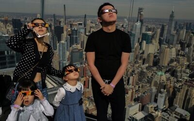 الناس ينظرون نحو السماء في منصة المراقبة ’Edge at Hudson Yards’ أثناء كسوف الشمس الكلي، في مدينة نيويورك في 8 أبريل، 2024. (Charly TRIBALLEAU / AFP)