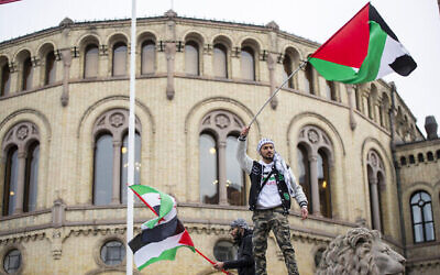 رجل يلوح بالعلم الفلسطيني أمام مبنى البرلمان النرويجي خلال مظاهرة في أوسلو، 28 أكتوبر، 2023. (Frederik Ringnes/NTB via AP)