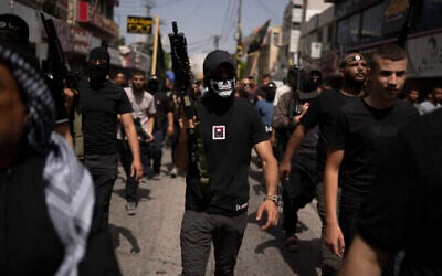 مسلحون يسيرون بينما يحمل المشيعون جثث الفلسطينيين، بعضها ملفوف بأعلام حركة الجهاد الإسلامي، خلال جنازتهم في مدينة جنين بالضفة الغربية، 23 مايو، 2024. (AP Photo / Leo Correa)