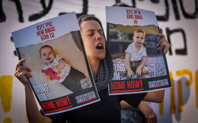 طالبة إسرائيلية تحمل صور رهائن خلال مظاهرة تطالب بإطلاق سراحهم بالقرب من الكنيست في القدس، 13 يونيو، 2024. (Chaim Goldberg/Flash90)