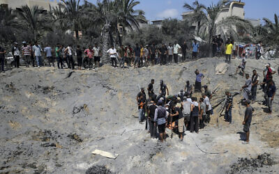 فلسطينيون يتفقدون الحفرة الناجمة عن قصف إسرائيلي استهدف القائد العسكري لحماس محمد الضيف في خان يونس جنوب قطاع غزة، 13 يوليو 2024. (AP Photo/Jehad Alshrafi)