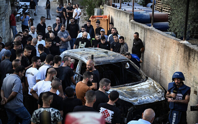 الناس يحيطون بسيارة محترقة في بلدة الزبابدة بمنطقة جنين في الضفة الغربية في 30 أغسطس 2024، بعد غارة لطائرة مسيّرة إسرائيلية ضد مسلحين فلسطينيين. (Ronaldo Schemidt/AFP) الناس يحيطون بسيارة محترقة في بلدة الزبابدة بمنطقة جنين في الضفة الغربية في 30 أغسطس 2024، بعد غارة لطائرة مسيّرة إسرائيلية ضد مسلحين فلسطينيين. (Ronaldo Schemidt/AFP)
