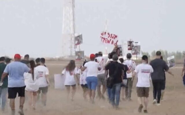 لقطة شاشة من مقطع فيديو يظهر أقارب الرهائن الإسرائيليين المحتجزين في غزة يتظاهرون في كيبوتس نيريم على طول السياج الحدودي بين إسرائيل وغزة، 29 أغسطس، 2024. (Nir Kafri/AFPTV/AFP) لقطة شاشة من مقطع فيديو يظهر أقارب الرهائن الإسرائيليين المحتجزين في غزة يتظاهرون في كيبوتس نيريم على طول السياج الحدودي بين إسرائيل وغزة، 29 أغسطس، 2024. (Nir Kafri/AFPTV/AFP)