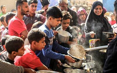 فلسطينيون يالقون مساعدات غذائية في مخيم البريج للاجئين في وسط قطاع غزة، 6 نوفمبر 2024 (Eyad BABA / AFP)