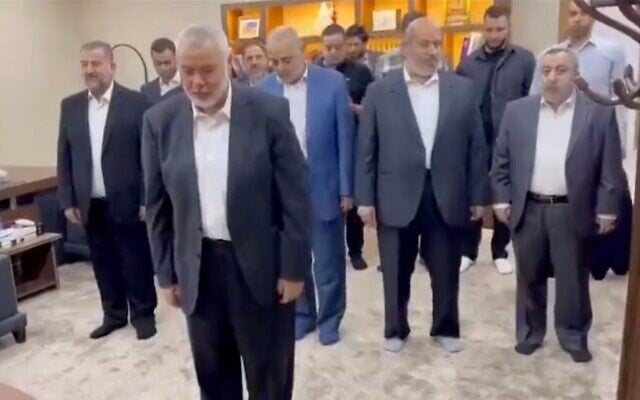 زعيم حماس إسماعيل هنية وأعضاء آخرين من حماس يصلون أثناء بث لقطات من هجوم حماس في 7 أكتوبر 2023 على شاشة التلفزيون. (Screen capture/X)