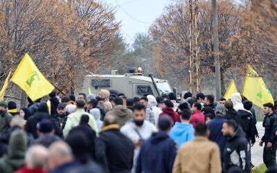 متظاهرون يحملون أعلام حزب الله أمام مركبة عسكرية إسرائيلية في برج الملوك في 26 يناير 2025 (Rabih DAHER / AFP)