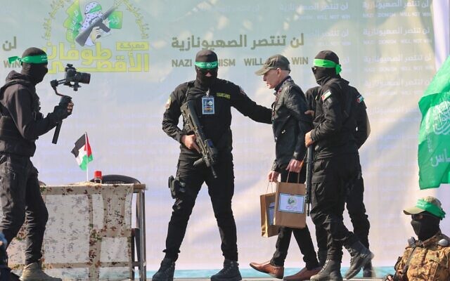 مسلحون من حركة حماس يرافقون الرهينة الأمريكي الإسرائيلي كيث سيغل على خشبة منصة قبل تسليمه إلى فريق الصليب الأحمر في مدينة غزة في 1 فبراير 2025، كجزء من عملية تسليم الرهائن الرابعة. (Omar AL-QATTAA / AFP)