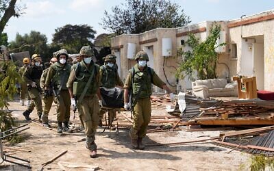 جنود إسرائيليون يحملون جثامين إسرائيليين في كيبوتس كفار عزة في 10 أكتوبر 2023. (AP Photo/Ohad Zwigenberg, File)