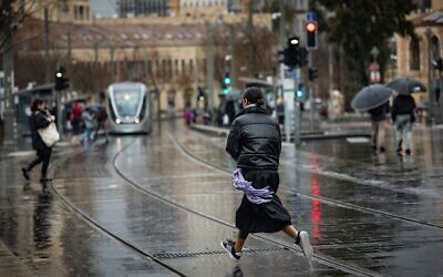 أشخاص يسيرون تحت المطر في شارع يافا في القدس، 5 فبراير 2025. (Yonatan Sindel/Flash90)