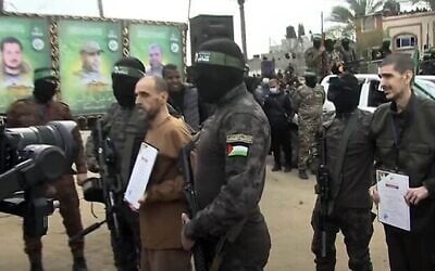 مسلحون من حماس يسيرون مع إيلي شرعبي في دير البلح وسط قطاع غزة قبل إطلاق سراحه، 8 فبراير، 2025. (Screengrab/YouTube)