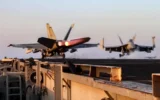 صورة مأخوذة من مقطع فيديو نشره القيادة المركزية الأمريكية (CENTCOM) في 15 مارس 2025، تظهر طائرة مقاتلة أمريكية من طراز F/A-18 تقلع من حاملة طائرات في البحر، وسط عمليات ضد الحوثيين في اليمن. (DVIDS / AFP)