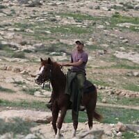 إسرائيلي مقيم في مستوطنة في منطقة تلال جنوب الخليل بالضفة الغربية يركب حصانه متوجها إلى تجمع خربة زنوتا الفلسطيني المهجور، 10 مارس، 2024. (Jeremy Sharon/Times of Israel)