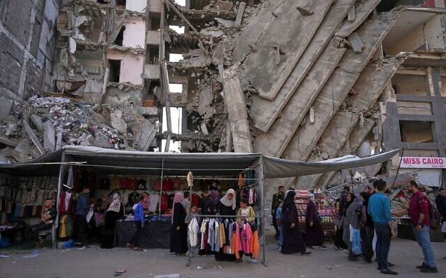 فلسطينيون يشترون الملابس من متجر بجوار مبنى سكني مدمر استعدادًا لاحتفالات عيد الفطر في حي الرمال وسط مدينة غزة، 28 مارس، 2025. (AP Photo/Jehad Alshrafi) فلسطينيون يشترون الملابس من متجر بجوار مبنى سكني مدمر استعدادًا لاحتفالات عيد الفطر في حي الرمال وسط مدينة غزة، 28 مارس، 2025. (AP Photo/Jehad Alshrafi)