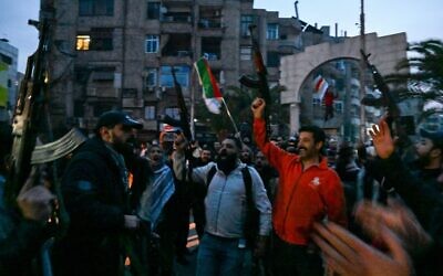 سكان محليون يرددون هتافات وهم يتجمعون في أحد شوارع مدينة جرمانا بضواحي دمشق في 8 ديسمبر، 2024. (LOUAI BESHARA / AFP)