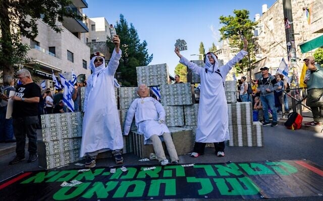 متظاهرون يسخرون من رئيس الوزراء بنيامين نتنياهو، الذي تم استجوابه في ذلك اليوم في التحقيق في علاقات مساعديه مع قطر، ويشيرون إلى سياسته في تسهيل المدفوعات القطرية إلى غزة التي تديرها حماس لسنوات؛ القدس، 31 مارس 2025. (Yonatan Sindel/Flash90) متظاهرون يسخرون من رئيس الوزراء بنيامين نتنياهو، الذي تم استجوابه في ذلك اليوم في التحقيق في علاقات مساعديه مع قطر، ويشيرون إلى سياسته في تسهيل المدفوعات القطرية إلى غزة التي تديرها حماس لسنوات؛ القدس، 31 مارس 2025. (Yonatan Sindel/Flash90)