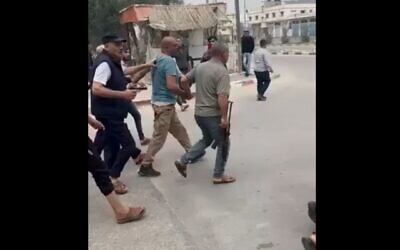 لقطة شاشة لمقطع فيديو على وسائل التواصل الاجتماعي يظهر فيه أفراد مسلحون من عائلة أبو سمرة يمسكون أحد أفراد حماس من ذراعه، والذي أعدموه لاحقًا بتهمة قتل أحد أفراد عائلتهم، دير البلح، قطاع غزة، 1 أبريل، 2025. (Screenshot from X, used in accordance with Clause 27a of the Copyright Law)