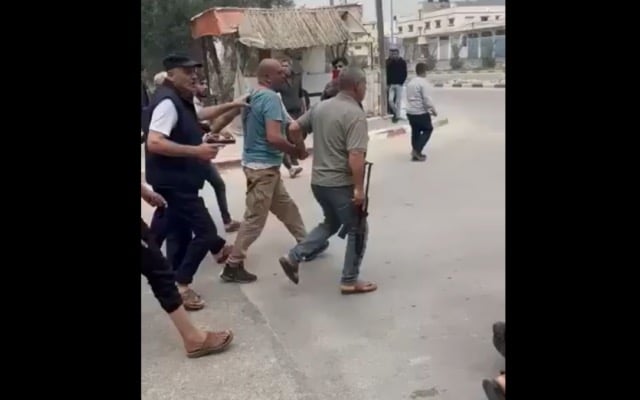 لقطة شاشة لمقطع فيديو على وسائل التواصل الاجتماعي يظهر فيه أفراد مسلحون من عائلة أبو سمرة يمسكون أحد أفراد حماس من ذراعه، والذي أعدموه لاحقًا بتهمة قتل أحد أفراد عائلتهم، دير البلح، قطاع غزة، 1 أبريل، 2025. (Screenshot from X, used in accordance with Clause 27a of the Copyright Law) لقطة شاشة لمقطع فيديو على وسائل التواصل الاجتماعي يظهر فيه أفراد مسلحون من عائلة أبو سمرة يمسكون أحد أفراد حماس من ذراعه، والذي أعدموه لاحقًا بتهمة قتل أحد أفراد عائلتهم، دير البلح، قطاع غزة، 1 أبريل، 2025. (Screenshot from X, used in accordance with Clause 27a of the Copyright Law)
