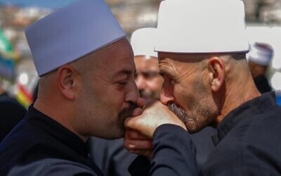 رجال دين دروز يتبادلون التحية أثناء انتظارهم وصول نظرائهم من سوريا في حافلة عبر حاجز حدودي يحرسه جنود إسرائيليون، بالقرب من قرية مجدل شمس في هضبة الجولان، في 25 أبريل 2025. (Photo by Jalaa MAREY / AFP)