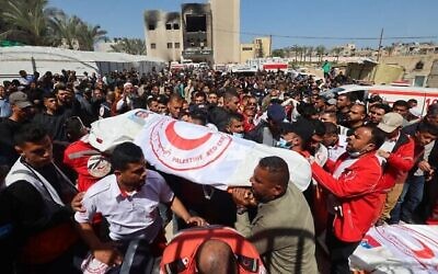 أفراد من الهلال الأحمر الفلسطيني وخدمات طوارئ أخرى يحملون جثامين زملائهم الذين يُزعم أنهم قُتلوا قبل أسبوع على يد القوات الإسرائيلية، خلال موكب تشييع في مستشفى ناصر في خان يونس جنوب قطاع غزة في 31 مارس، 2025.  (Eyad BABA / AFP)
