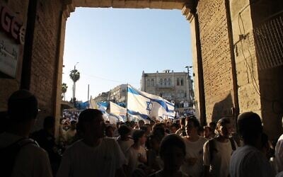 إسرائيليون يمينيون يسيرون عبر باب العامود إلى الحي العربي في البلدة القديمة بالقدس خلال "مسيرة الأعلام" السنوية في يوم القدس، 5 يونيو 2024. (Sam Sokol/Times of Israel)