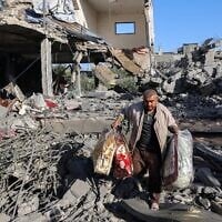 رجل فلسطيني يحمل أغراضاً انتشلها من منزل استهدفته غارة إسرائيلية في مخيم النصيرات في وسط قطاع غزة، 24 مايو 2025. (Eyad Baba/AFP)