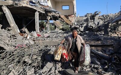 رجل فلسطيني يحمل أغراضاً انتشلها من منزل استهدفته غارة إسرائيلية في مخيم النصيرات في وسط قطاع غزة، 24 مايو 2025. (Eyad Baba/AFP)