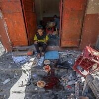 أطفال فلسطينيون ينتشلون الخبز من مخبز مرتجل قصفته الغارات الإسرائيلية على مخيم النصيرات للاجئين في وسط قطاع غزة في 8 مايو 2025. (Eyad BABA / AFP)