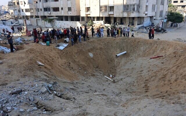 فلسطينيون يتجمعون حول حفرة ضخمة بعد أن ضربت غارة إسرائيلية خيام النازحين في حي الرمال شمال مدينة غزة في 28 يونيو 2025. (Omar AL-QATTAA / AFP)