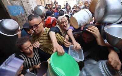 فلسطينيون يقفون في طابور أمام مركز لتوزيع المواد الغذائية في النصيرات، وسط قطاع غزة، في 23 يونيو 2025.  (Eyad BABA / AFP)