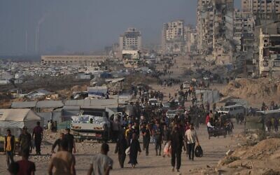 فلسطينيون نازحون يسيرون بين أنقاض المباني المدمرة على طول ساحل مدينة غزة، 9 يونيو 2025. (AP Photo/Jehad Alshrafi)