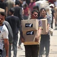 أشخاص يحملون صناديق إغاثة وزعتها مؤسسة غزة الإنسانية المدعومة من الولايات المتحدة وإسرائيل في مركز لتوزيع المساعدات في وسط قطاع غزة في 29 مايو 2025. (Eyad BABA / AFP)