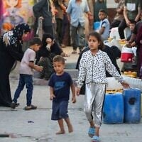 يصطف الفلسطينيون بحاوياتهم في انتظار شاحنة توزيع المياه في مخيم مؤقت للنازحين تعرض لقصف إسرائيلي في اليوم السابق، على أرض مدرسة أبو الحلو للبنات التي تديرها الأونروا في مخيم البريج للاجئين في وسط قطاع غزة في 17 يوليو 2025. (إياد بابا / أ ف ب)