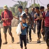 فلسطينيون يحملون أمتعتهم الشخصية أثناء سيرهم في منطقة المواصي في رفح جنوب قطاع غزة في 28 يوليو 2025. (أ ف ب)