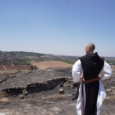 الصورة الرئيسية: الأخ أثناسيوس، راهب كاثوليكي في دير في اللطرون، ينظر إلى الأضرار التي سببتها حرائق الغابات في كروم العنب والزيتون التابعة للدير، في 16 يوليو 2025.(Charlie Summers/Times of Israel)