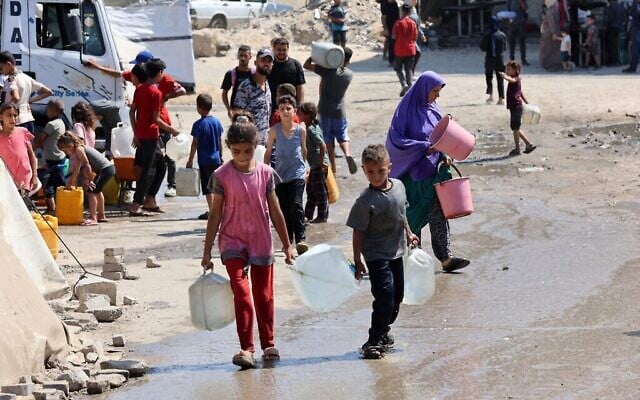أطفال فلسطينيون يحملون غالونات من المياه النظيفة من نقطة توزيع في مدينة غزة في 1 أغسطس 2025. (تصوير: عمر القطاع / وكالة فرانس برس)