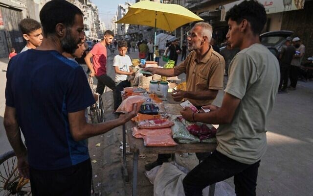 بائع فلسطيني يعرض بضائع للبيع في أحد أسواق الشوارع بمدينة غزة، 23 يوليو/تموز 2025. (صورة أسوشيتد برس/جهاد الشرفي)