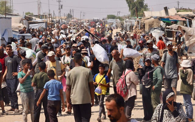 يحمل فلسطينيون مساعدات إنسانية تلقوها في معبر رفح أثناء سيرهم في منطقة المواصي في رفح جنوب قطاع غزة في 30 يوليو 2025. (أ ف ب)