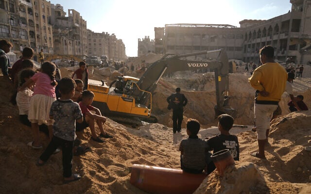 فلسطينيون يشاهدون آلات وبعض العمال من مصر يبحثون عن جثث الرهائن في مدينة حمد، في خان يونس، جنوب قطاع غزة، 26 أكتوبر/تشرين الأول 2025. (AP/Jehad Alshrafi) فلسطينيون يشاهدون آلات وبعض العمال من مصر يبحثون عن جثث الرهائن في مدينة حمد، في خان يونس، جنوب قطاع غزة، 26 أكتوبر/تشرين الأول 2025. (AP/Jehad Alshrafi)