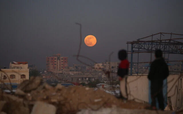 صورة توضيحية: أطفال فلسطينيون نازحون ينظرون إلى أول قمر عملاق لهذا العام، "قمر الذئب"، وهو يرتفع فوق مخيم البريج للاجئين في وسط قطاع غزة في 3 يناير 2026. (Eyad Baba/AFP) صورة توضيحية: أطفال فلسطينيون نازحون ينظرون إلى أول قمر عملاق لهذا العام، "قمر الذئب"، وهو يرتفع فوق مخيم البريج للاجئين في وسط قطاع غزة في 3 يناير 2026. (Eyad Baba/AFP)