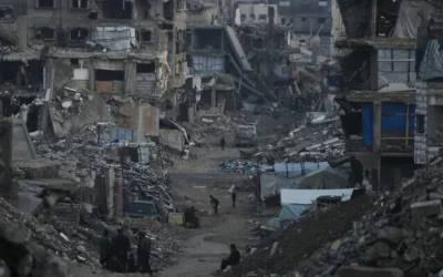 فلسطينيون يسيرون بين المباني التي دمرتها العمليات الجوية والبرية الإسرائيلية في مدينة غزة، 6 يناير/كانون الثاني 2026. (AP Photo/Jehad Alshrafi)