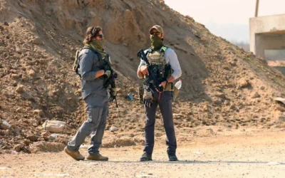 توضيحية: رجال مسلحون يقفون للحراسة عند نقطة تفتيش يديرها أمن أمريكي ومصري في ممر نتساريم، بينما يشق نازحون فلسطينيون طريقهم من الجنوب إلى الأجزاء الشمالية من قطاع غزة، على طريق صلاح الدين وسط غزة، في 29 يناير 2025. (Omar al-Qattaa/AFP)
