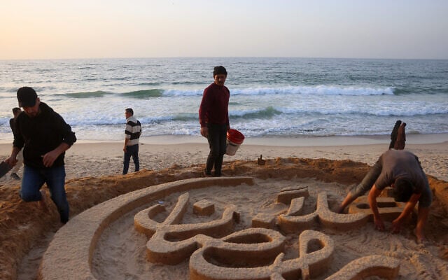 أشخاص يساعدون الفنان الفلسطيني يزيد أبو جراد، النازح بسبب الحرب من بيت لاهيا شمال قطاع غزة، أثناء قيامه بنحت مجسم رملي يحمل عبارة الترحيب "أهلاً رمضان" على شاطئ خان يونس جنوب الأراضي الفلسطينية في 17 فبراير 2026، وذلك قبل يوم واحد من بدء شهر رمضان المبارك. (Photo by Bashar Taleb / AFP) أشخاص يساعدون الفنان الفلسطيني يزيد أبو جراد، النازح بسبب الحرب من بيت لاهيا شمال قطاع غزة، أثناء قيامه بنحت مجسم رملي يحمل عبارة الترحيب "أهلاً رمضان" على شاطئ خان يونس جنوب الأراضي الفلسطينية في 17 فبراير 2026، وذلك قبل يوم واحد من بدء شهر رمضان المبارك. (Photo by Bashar Taleb / AFP)