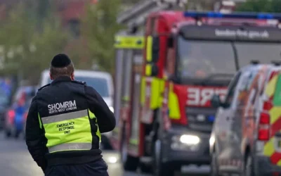 عضو في منظمة أمن مجتمعية يراقب فريق استجابة من رجال الإطفاء في لندن، الاثنين، 23 مارس 2026، بعد هجوم حرق عمد معادٍ للسامية على ما يبدو استهدف أربع مركبات تابعة لخدمة الإسعاف اليهودية، "هتسولا نورث ويست"، في لندن. (AP Photo/Alberto Pezzali)