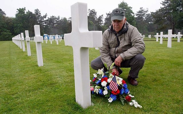 Paul Clifford, 70, from Boston MA, USA, places flowers on the grave of Walter J. Gunther Jr, the uncle of his best friend, in the Normandy American Cemetery and Memorial, in Colleville sur Mer, France, Wednesday June 4, 2014. (photo credit: AP Photo/Claude Paris)