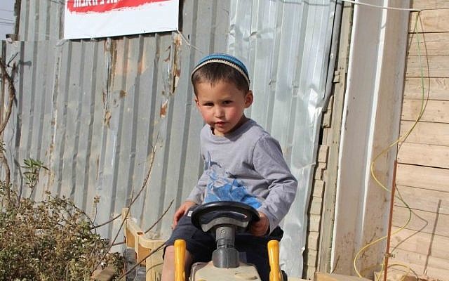 A child of Netiv Avot, where 17 homes are slated for destruction in March 2018. The sign behind him says, ‘No more destruction; normalize Netiv Avot.’ (Laura Ben-David)