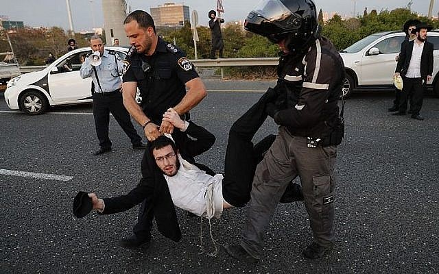 Police remove ultra-Orthodox demonstrators who are blocking a road during a protest against army conscription in the city of Bnei Brak, near Tel Aviv, on March 12, 2018. (AFP PHOTO / Ahmad GHARABLI)